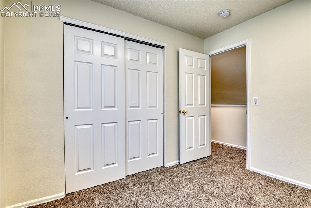 Image 33 of 43: Unfurnished bedroom with carpet, a textured ceiling, and a closet