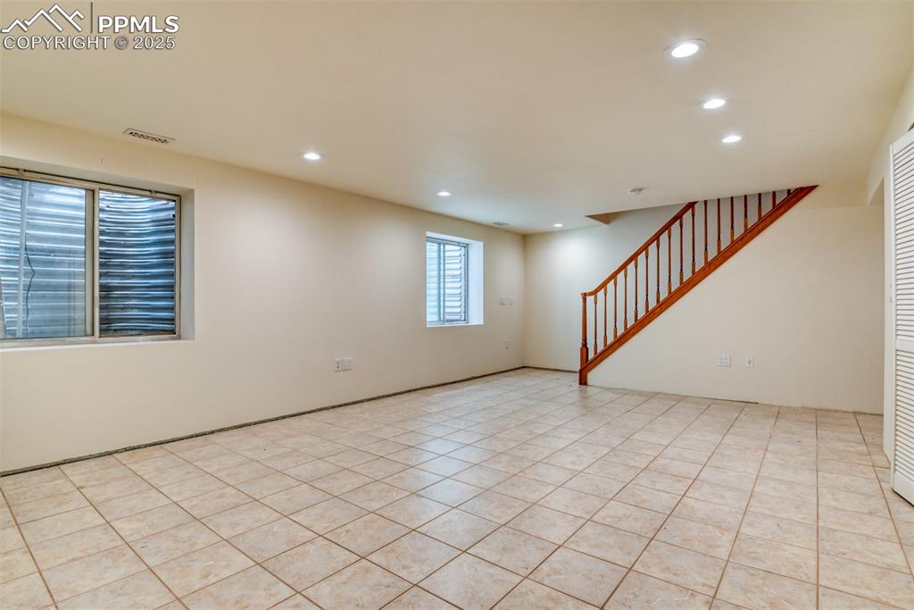 Image 37 of 43: Empty room featuring recessed lighting, light title flooring, and stairs