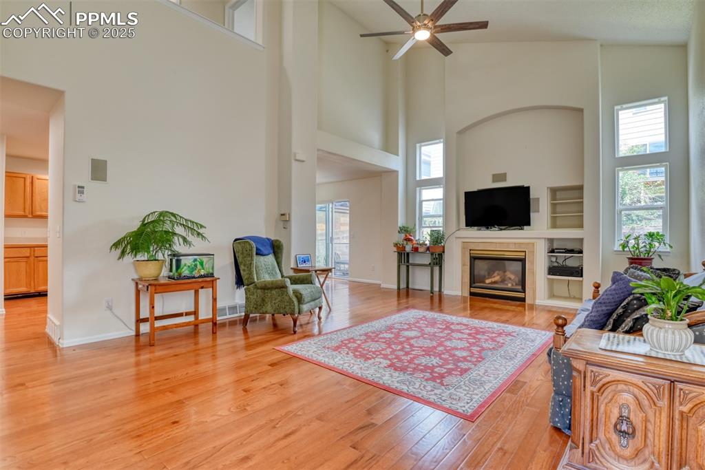 Image 4 of 43: Living area featuring light wood-type flooring, a fireplace, a ceiling fan,