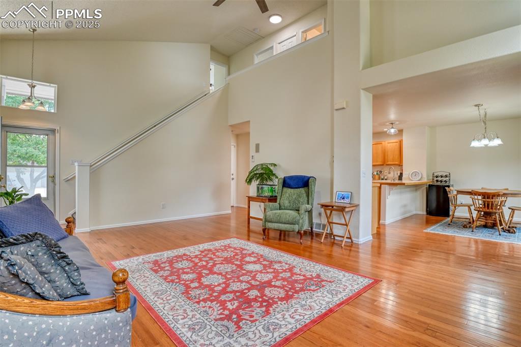 Image 6 of 43: Living area with high vaulted ceiling, a chandelier, light wood-type floori