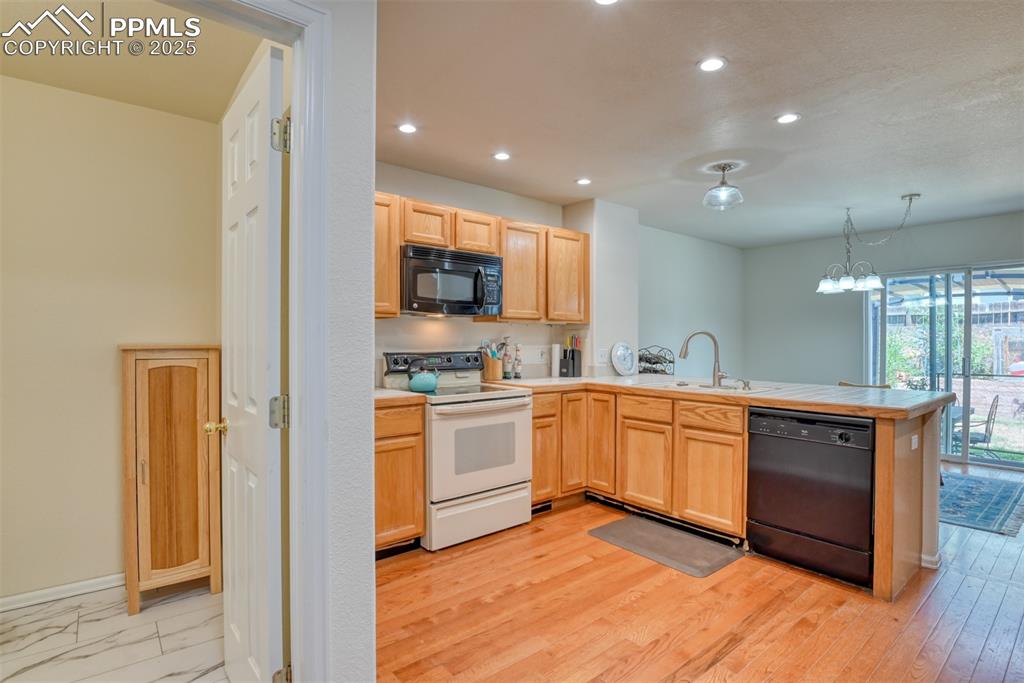 Image 8 of 43: Kitchen featuring black appliances, light brown cabinets, recessed lighting