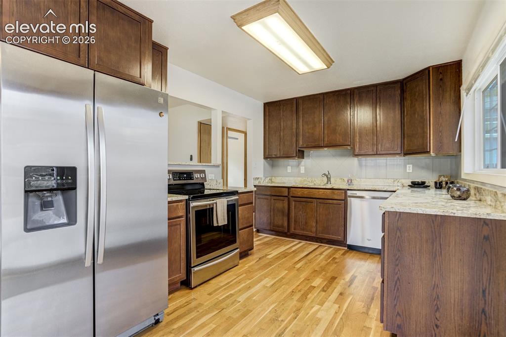 Image 11 of 31: Kitchen featuring stainless steel appliances, wood-finish flooring, granite