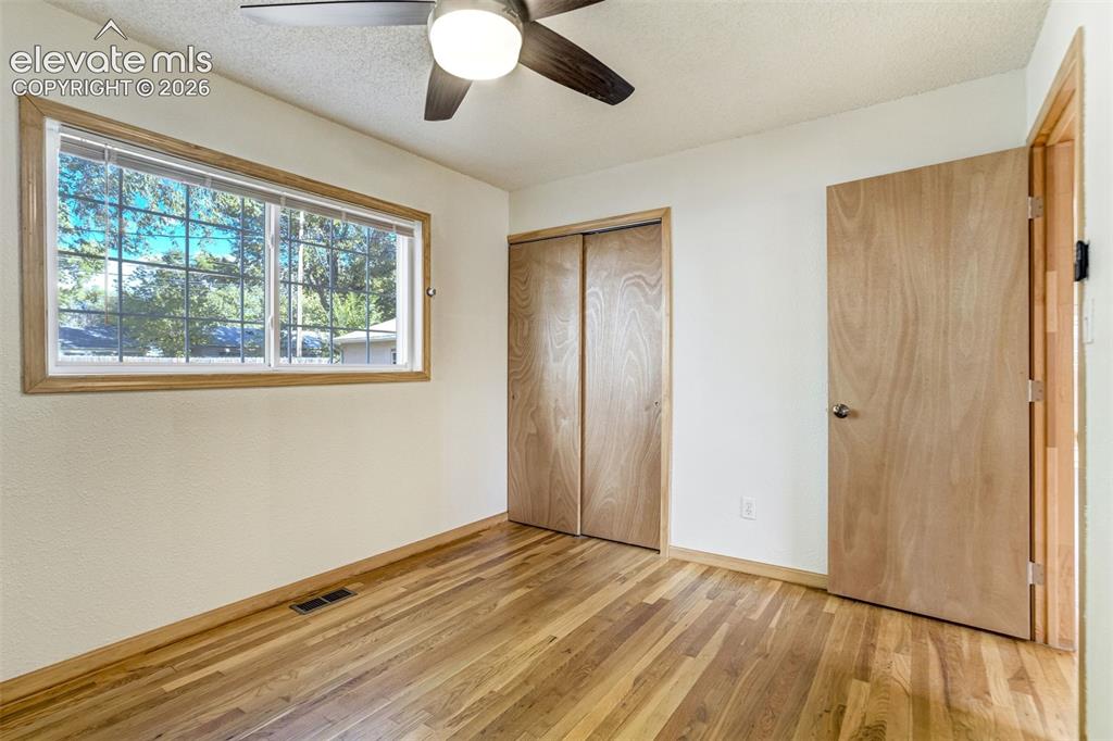 Image 15 of 31: Wood-finish flooring, wood-framed window, ceiling fan with integrated light