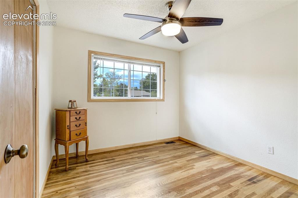 Image 20 of 31: Wood-finish flooring, white walls, and a ceiling fan with integrated lighti
