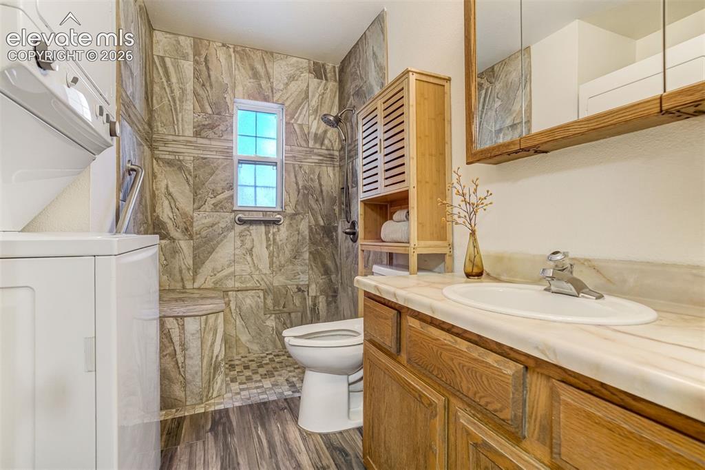Image 23 of 31: Floor-to-ceiling tile shower with integrated bench and grab bar, wood-finis