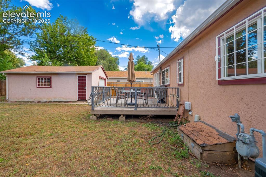 Image 29 of 31: Expansive yard featuring a raised deck, detached garage, and stucco exterio