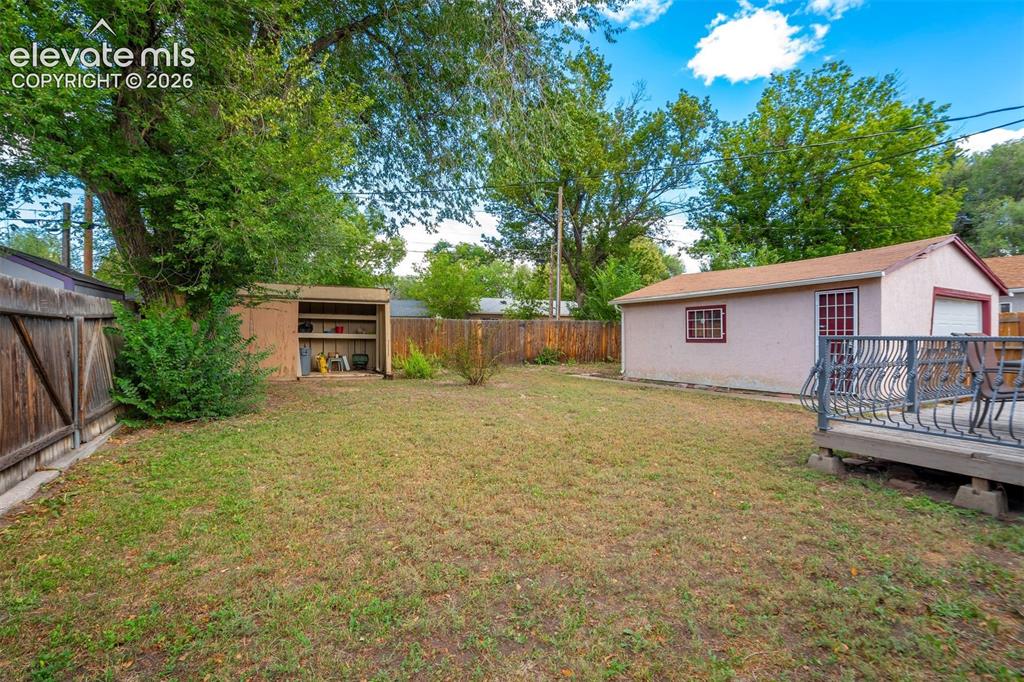 Image 31 of 31: Expansive backyard featuring a spacious detached garage, a wooden storage s
