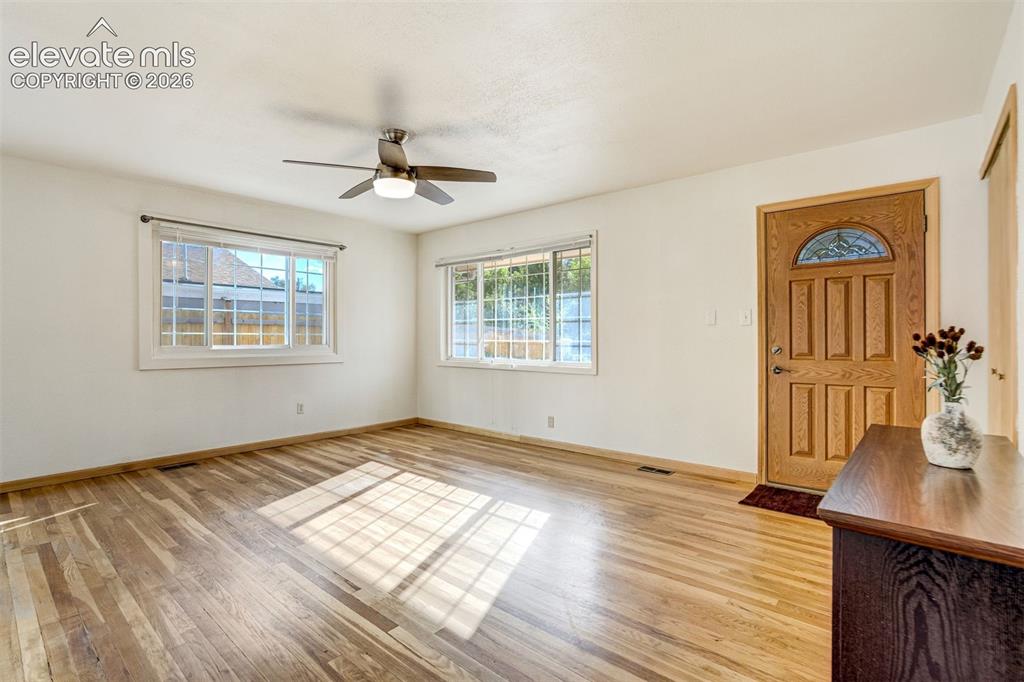 Image 6 of 31: Wood-finish flooring, multiple windows with white trim, a wood entry door w