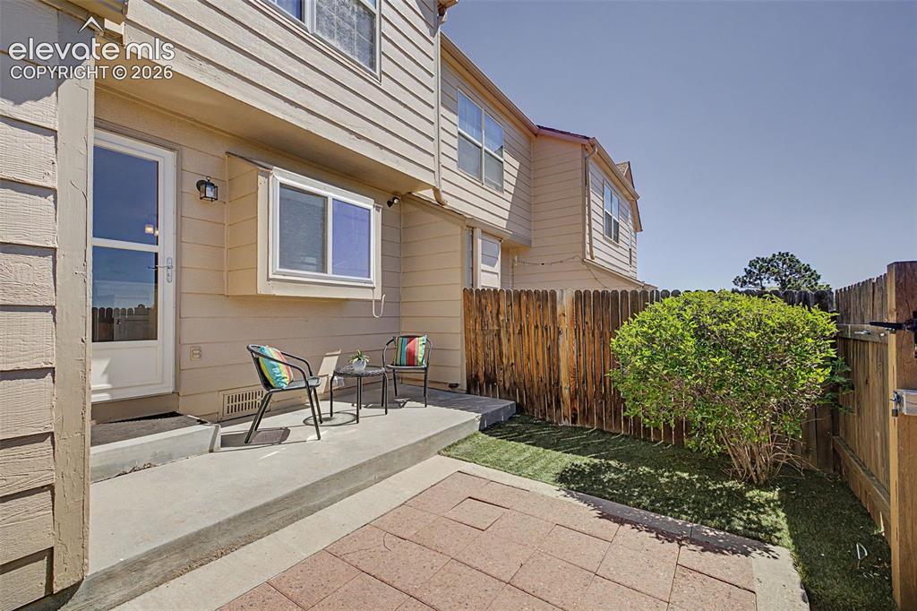 Image 28 of 31: Back of property, fenced, with concrete patio and turf