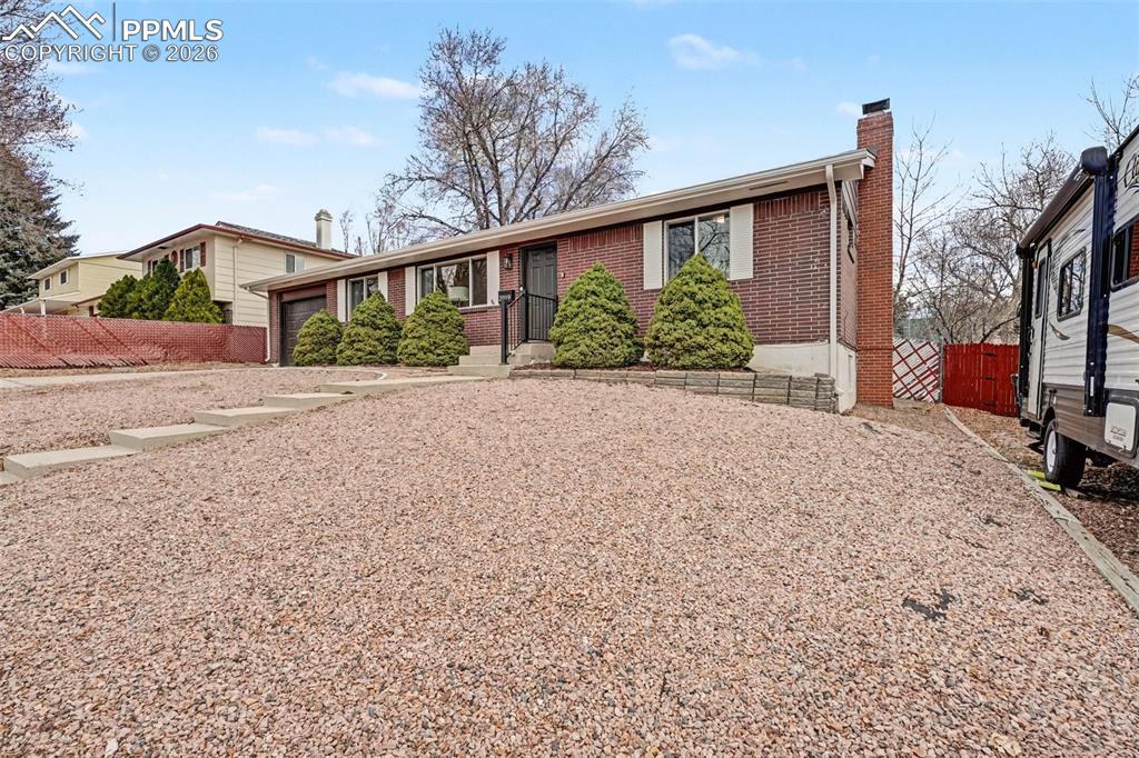 Image 21 of 23: Single story home with a chimney and brick siding