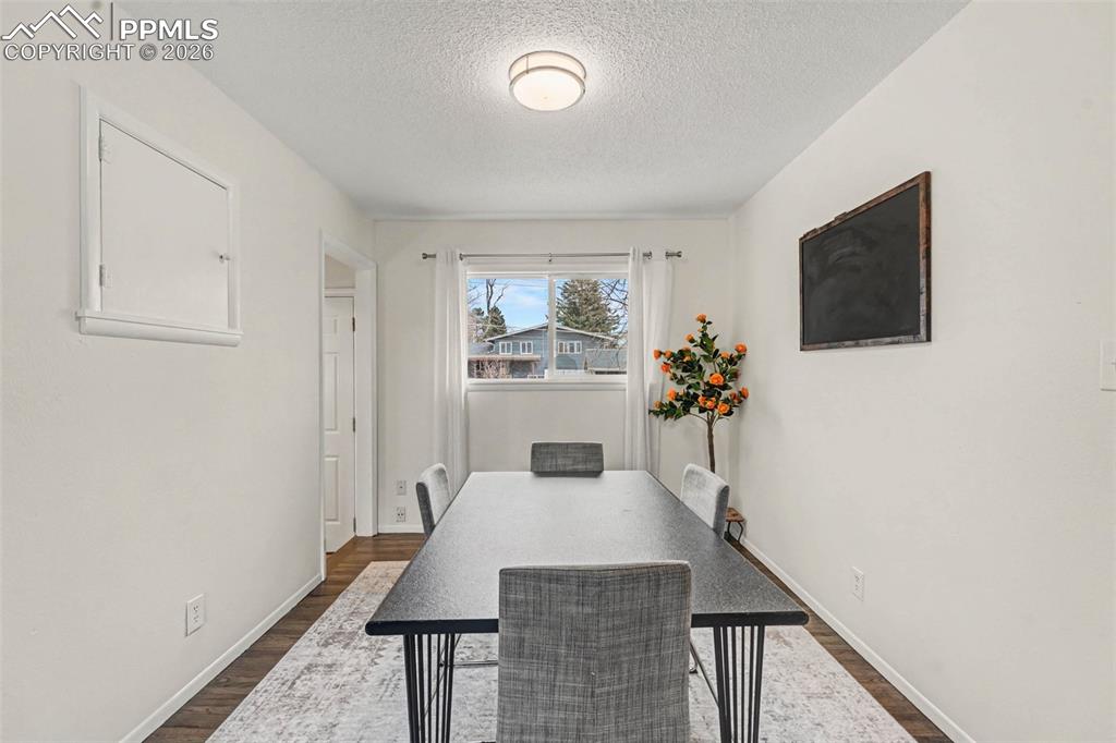 Image 4 of 23: Dining area with a textured ceiling and dark wood-style flooring
