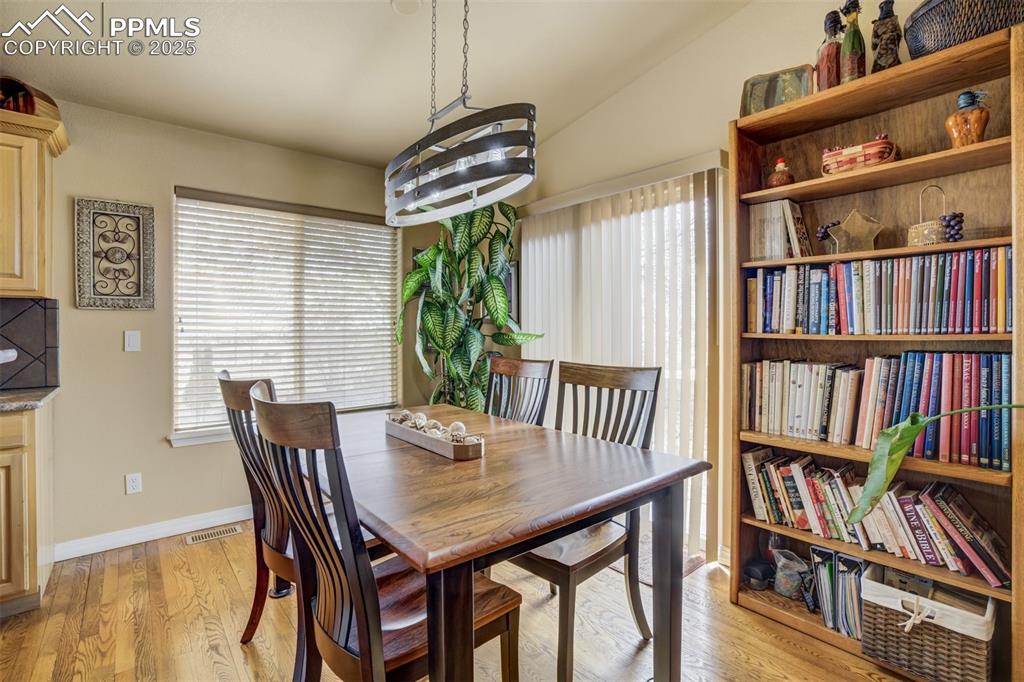 Image 14 of 50: Dining area, beautiful new light fixture, hardwood floors and slider to the