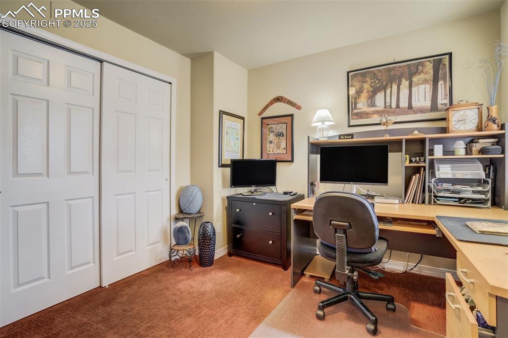 Image 20 of 50: Main Floor Bedroom 2, currently set up as an office. Large Closet. Carpet.