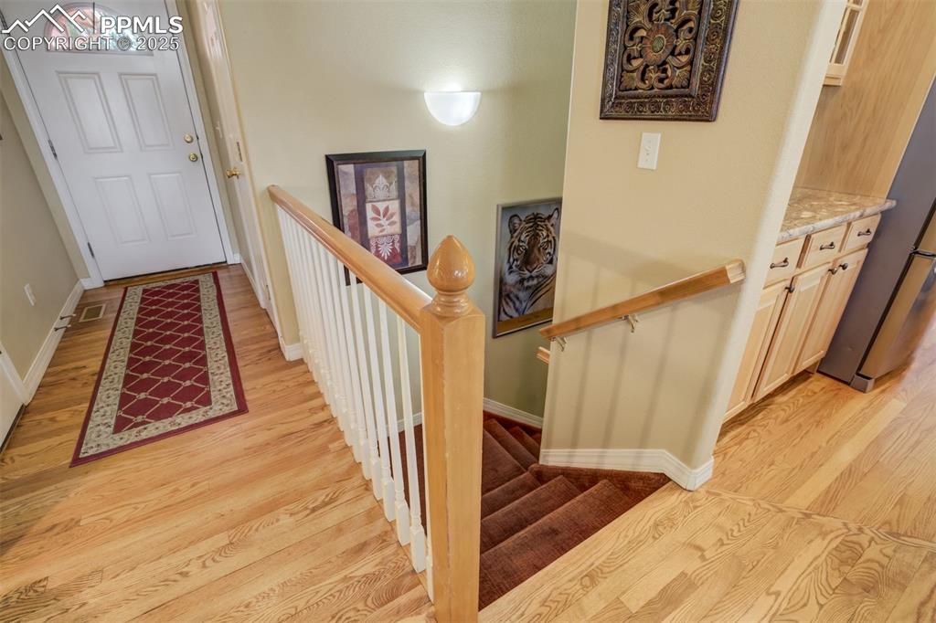 Image 26 of 50: Entrance foyer with hall closet and hardwood floors. Stairs down to the ba