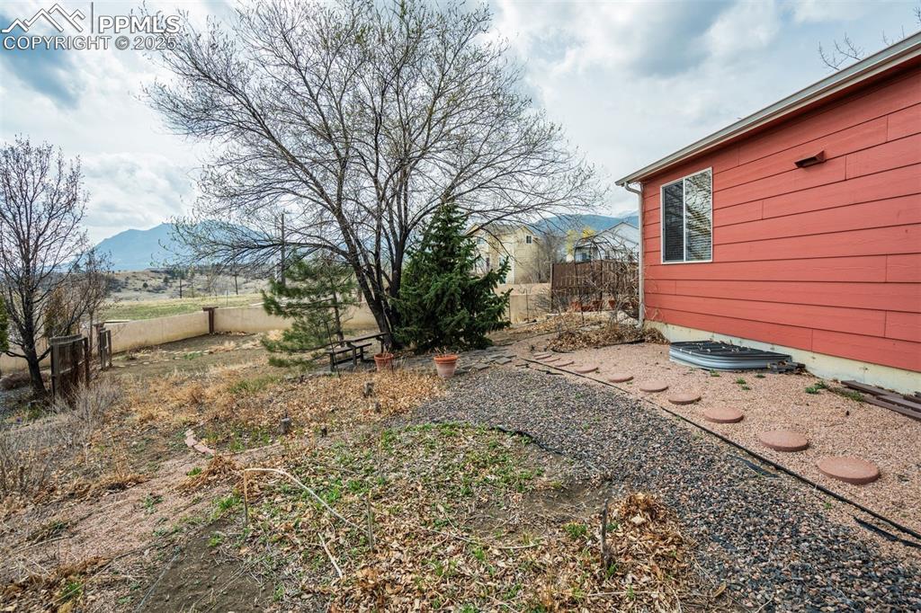 Image 43 of 50: Side view of the yard. All window wells have safety covers in place.
