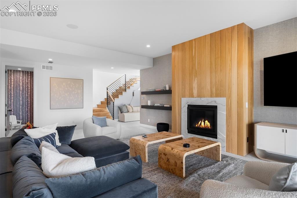 Image 10 of 37: Lower-level living area with fireplace and modern architectural detailing.