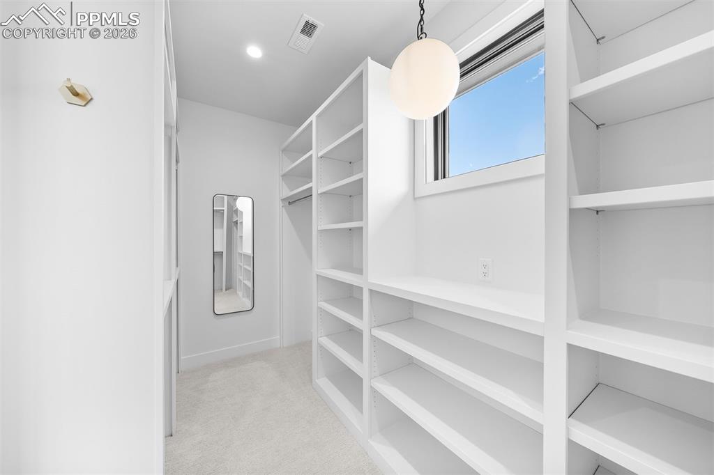 Image 21 of 37: Custom walk-in closet with full-height built-ins and natural light.
