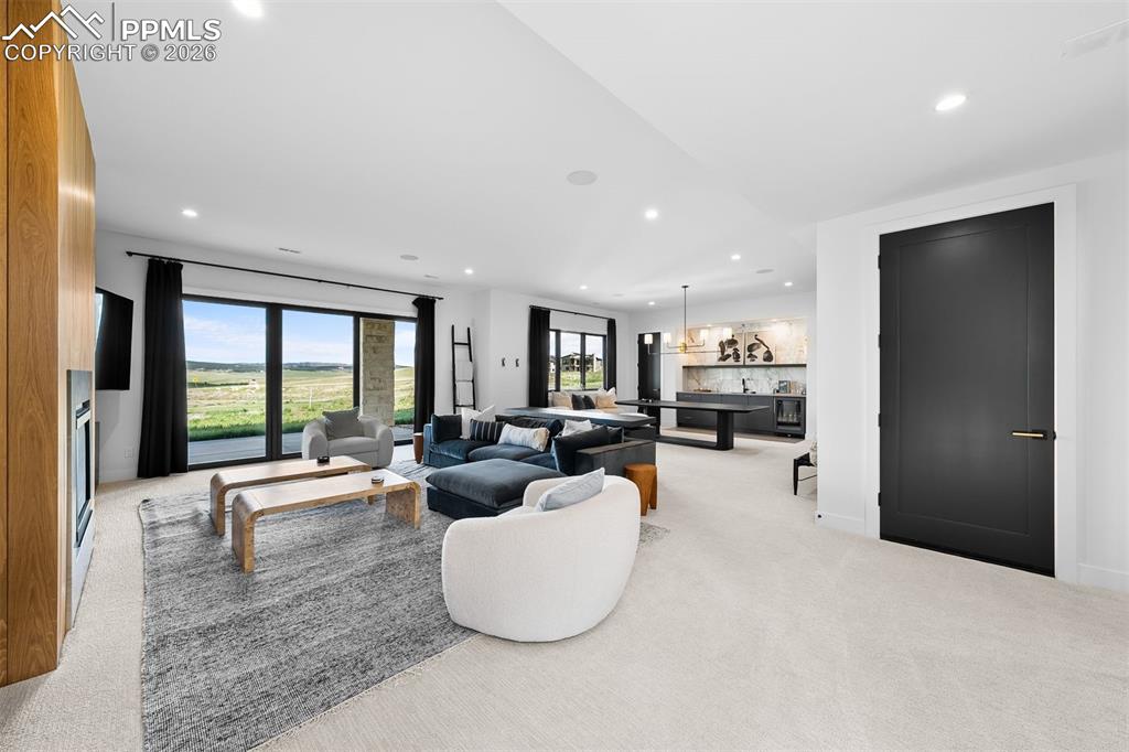 Image 22 of 37: Spacious lower-level living area with expansive windows and integrated wet 