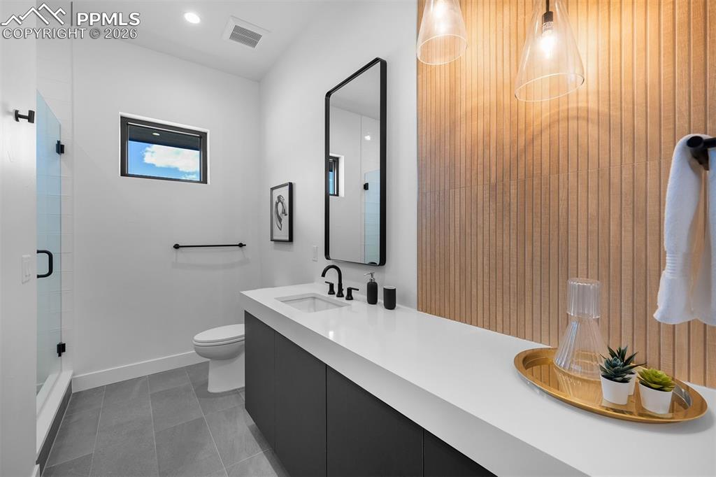 Image 26 of 37: Quartz vanity paired with vertical wood slat detailing and matte black fixt