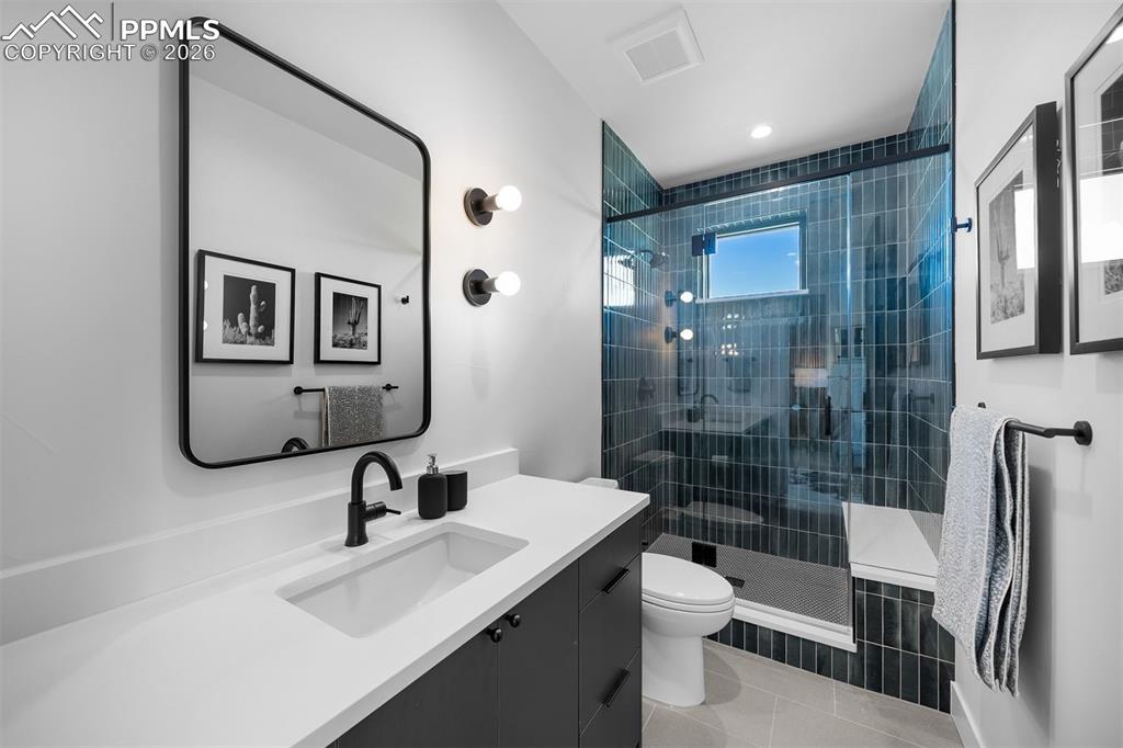 Image 28 of 37: Glass-enclosed shower with full-height blue tile and modern hardware.