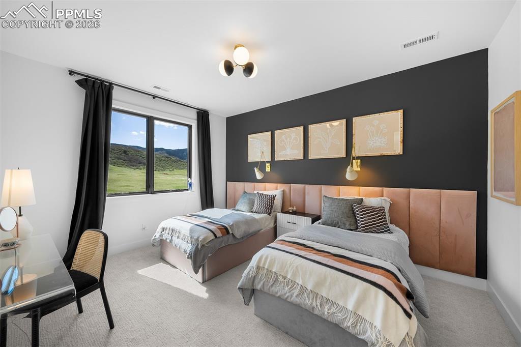 Image 29 of 37: Secondary bedroom with custom upholstered headboard and contrast accent wal