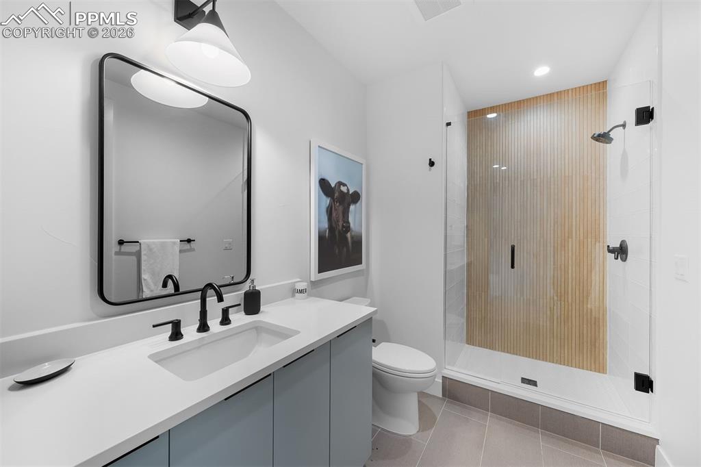 Image 32 of 37: Glass-enclosed shower with vertical wood tile accent and clean-lined vanity