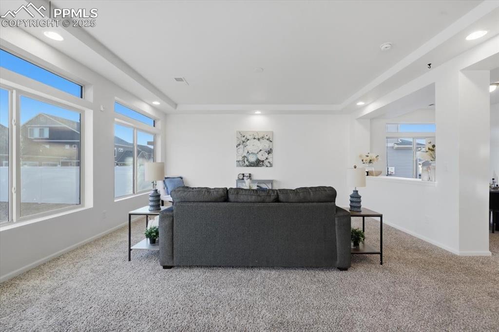 Image 13 of 41: Living room featuring light carpet, a tray ceiling, and recessed lighting