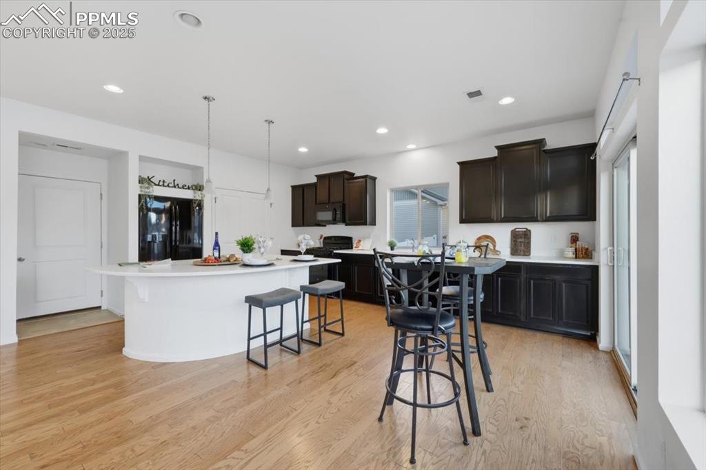 Image 17 of 41: Kitchen featuring light wood-type flooring, black appliances, a breakfast b