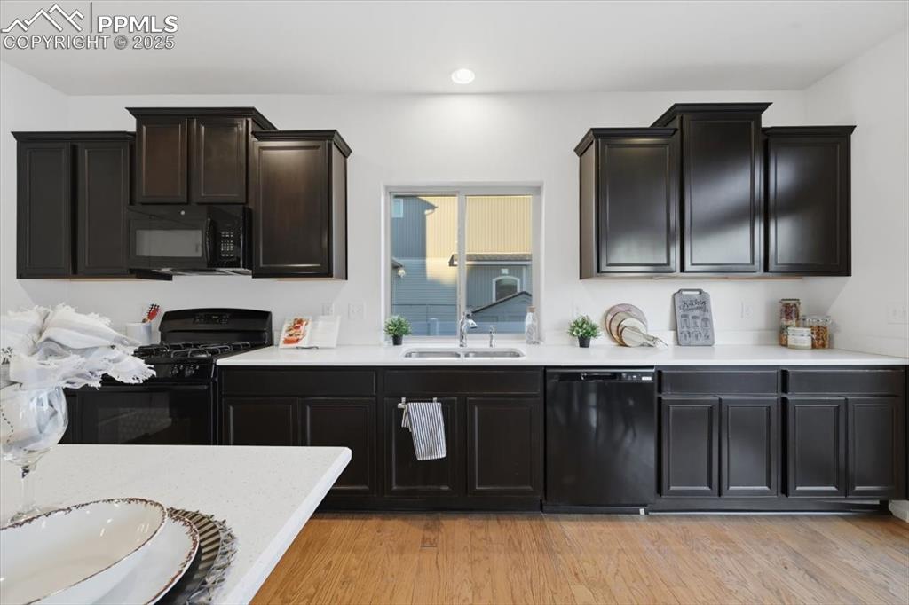 Image 18 of 41: Kitchen featuring black appliances, light wood-style floors, light stone co