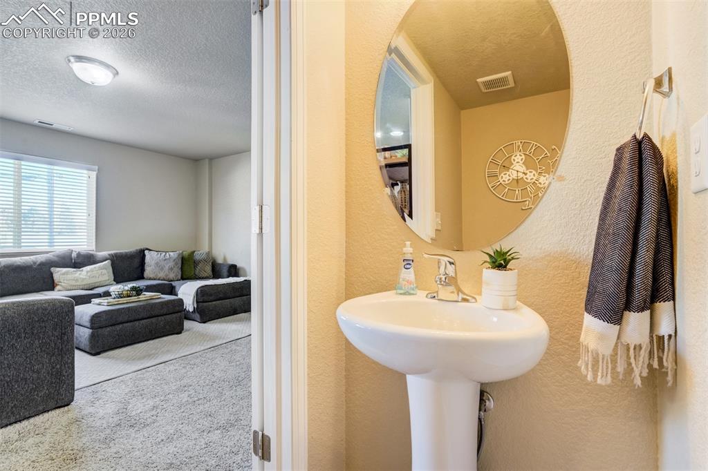 Image 10 of 50: Convenient main-level powder room with pedestal sink, modern mirror, and st