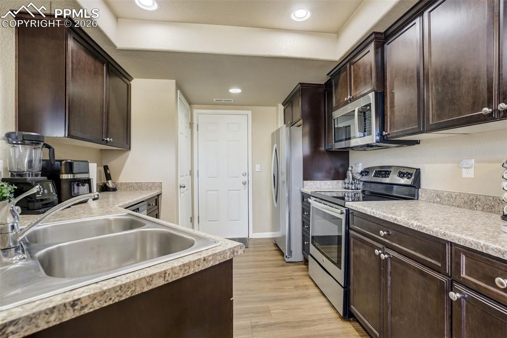Image 15 of 50: Bright and functional kitchen with rich cabinetry, solid surface countertop