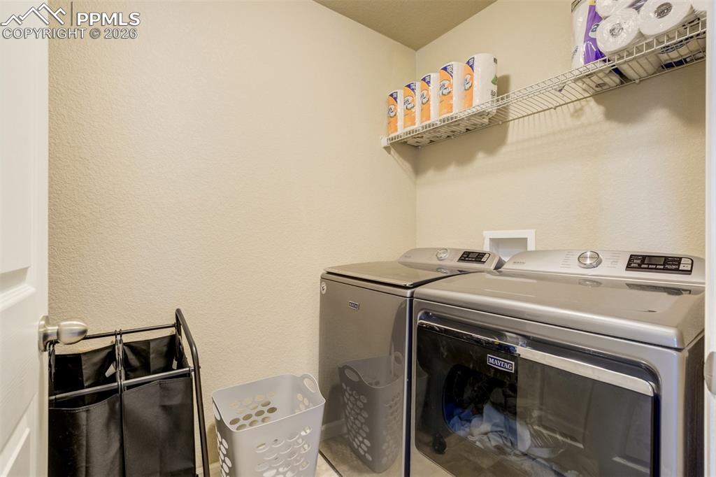 Image 21 of 50: Dedicated laundry room with washer and dryer, built-in shelving, and additi