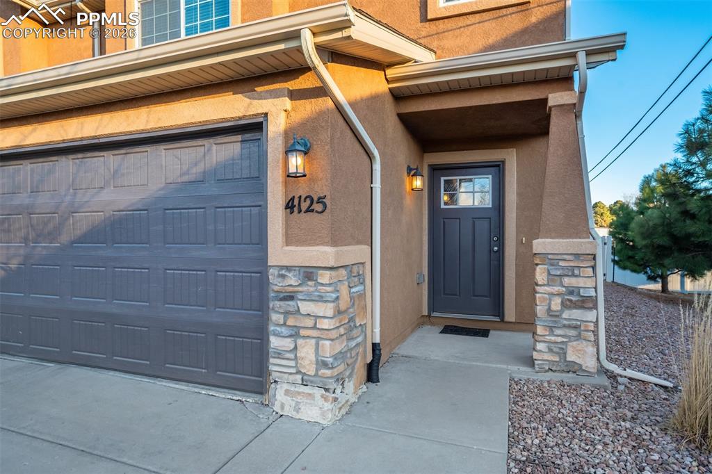 Image 3 of 50: Inviting front entry with covered porch, stone accents, and private access