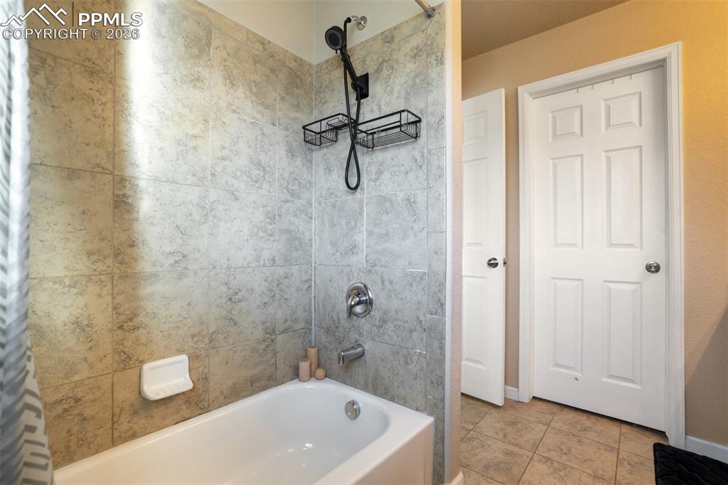 Image 33 of 50: Primary bathroom includes a full tub/shower combo with tile surround and up