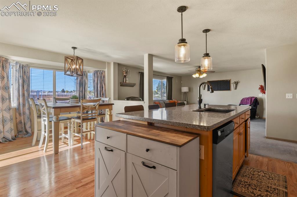Image 10 of 50: Kitchen with hanging light fixtures, wood counters, an island with sink, an