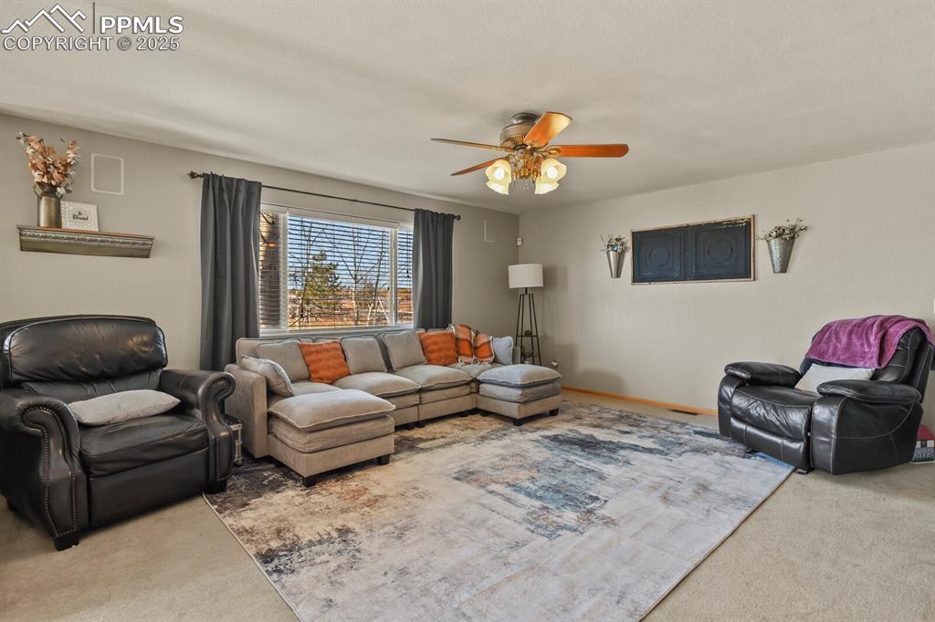 Image 16 of 50: Living room featuring carpet floors and a ceiling fan