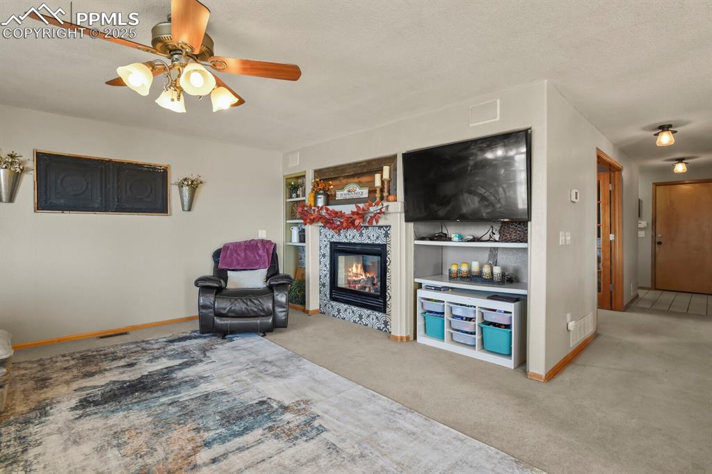 Image 17 of 50: Living area featuring light colored carpet, a fireplace, built in features,