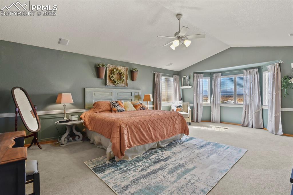 Image 21 of 50: Carpeted bedroom featuring lofted ceiling, a ceiling fan, and a textured ce