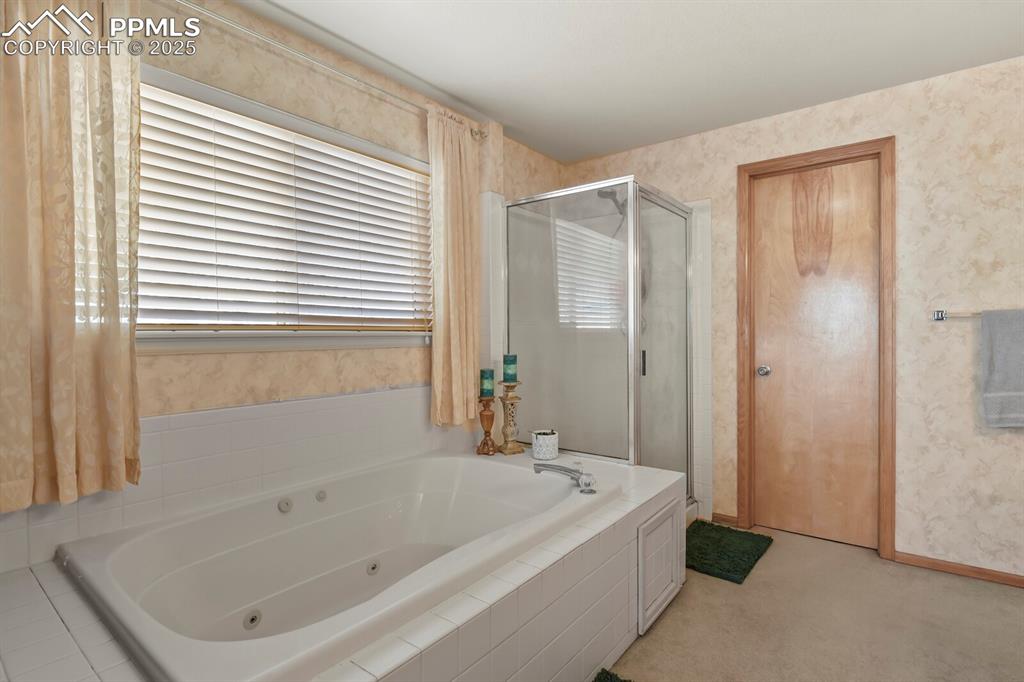 Image 24 of 50: Full bathroom featuring wallpapered walls, a tub with jets, a stall shower,