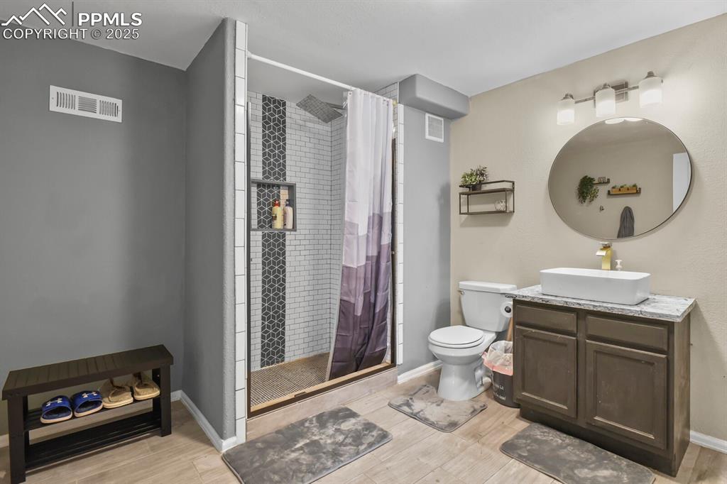 Image 35 of 50: Full bathroom with vanity, a shower stall, and light wood-style floors