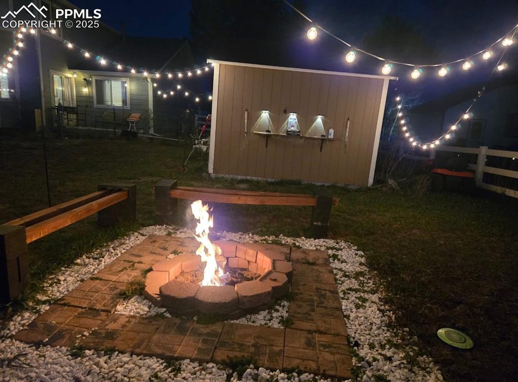 Image 36 of 50: Yard at night featuring a patio area and a lawn