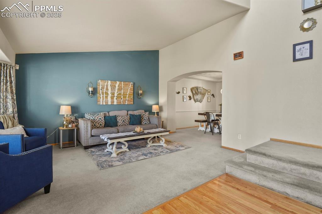 Image 4 of 50: Living room featuring arched walkways, carpet flooring, wood finished floor