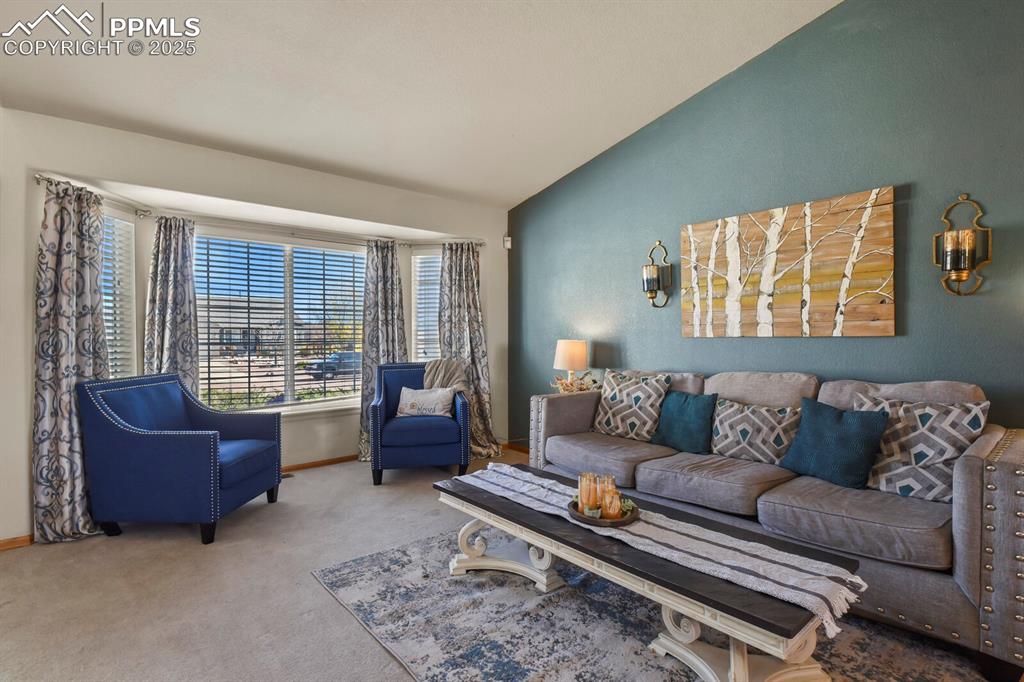 Image 6 of 50: Carpeted living room with vaulted ceiling and baseboards