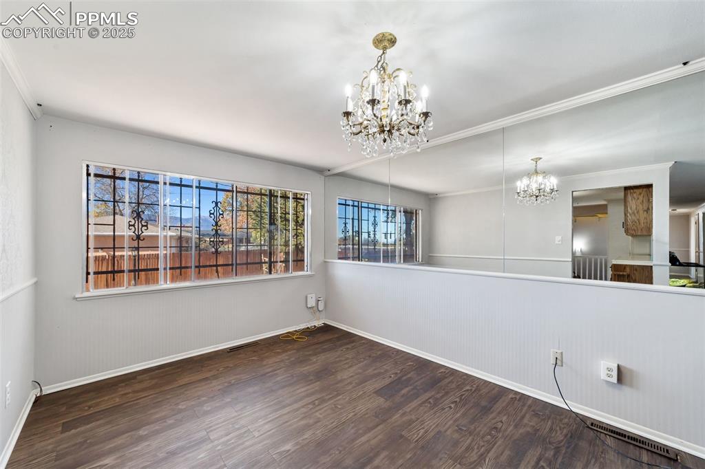 Image 12 of 49: Unfurnished dining area with dark wood-type flooring, a chandelier, and cro