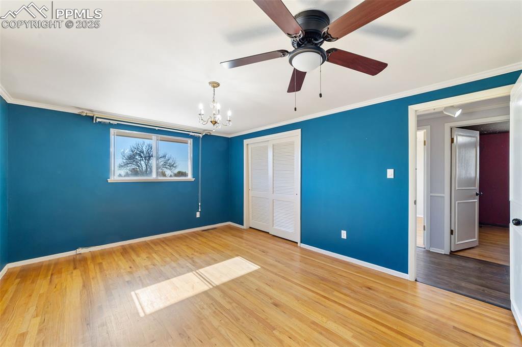 Image 14 of 49: Unfurnished bedroom with crown molding, wood finished floors, a closet, a c