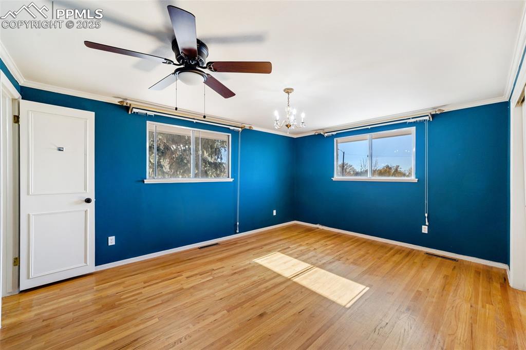 Image 15 of 49: Empty room with a chandelier, light wood-style flooring, ornamental molding