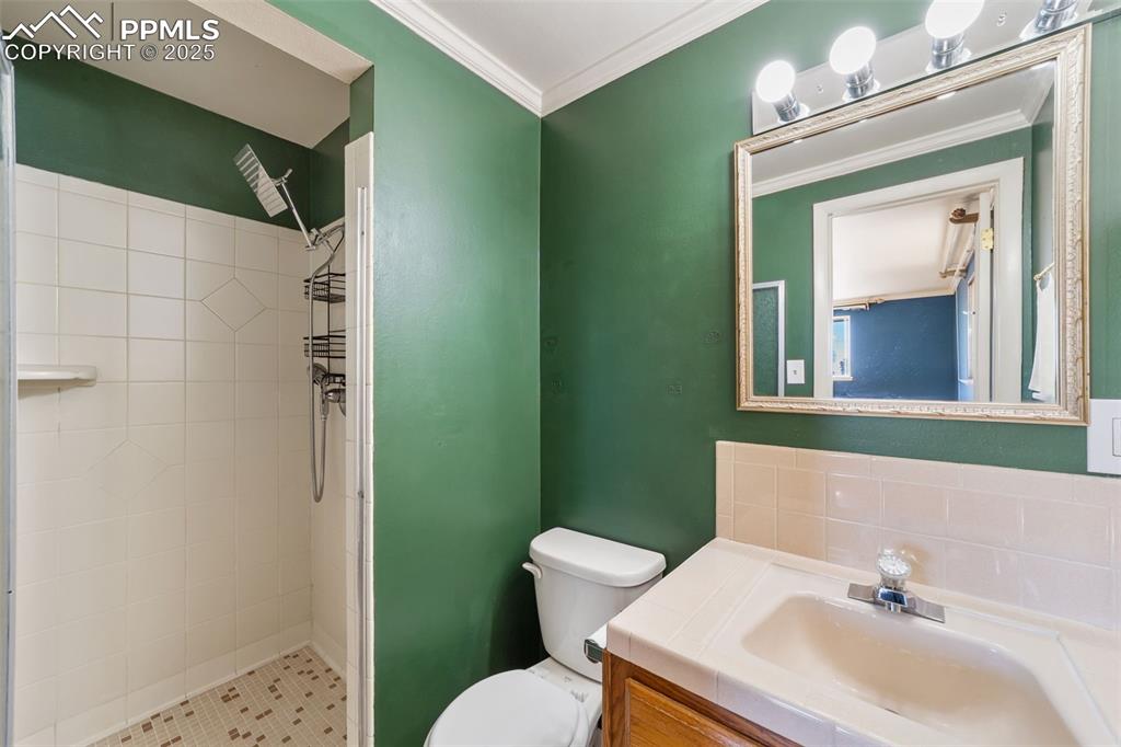 Image 18 of 49: Bathroom with a shower stall, vanity, and ornamental molding