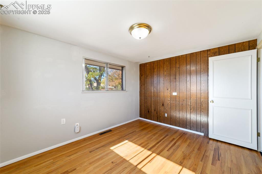 Image 20 of 49: Spare room with wood walls and light wood-style flooring