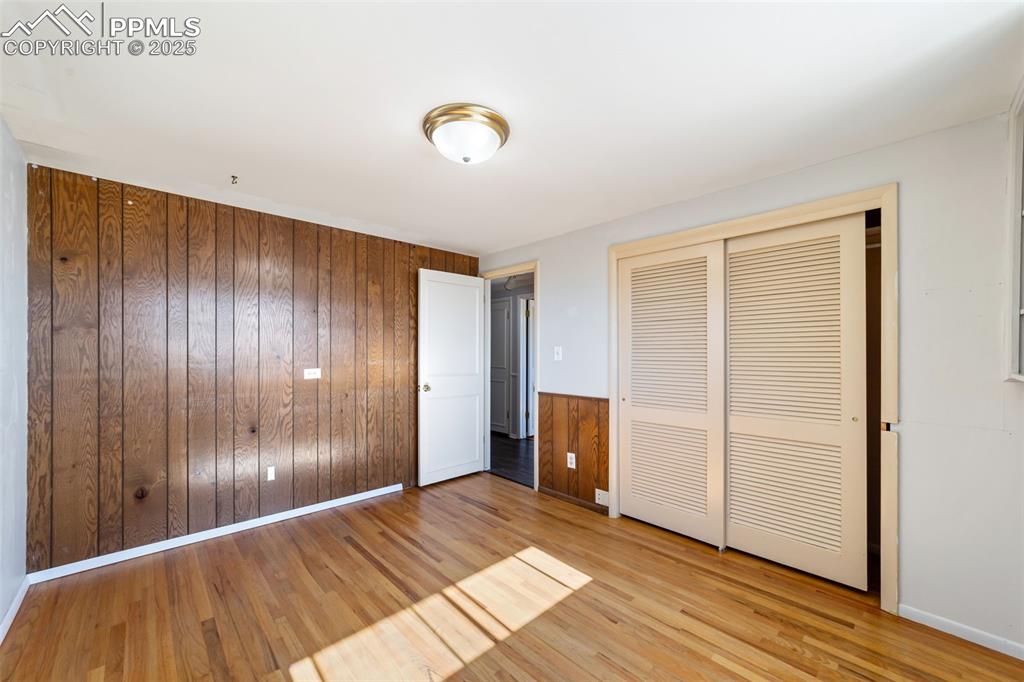 Image 21 of 49: Unfurnished bedroom featuring wooden walls, light wood-style flooring, and