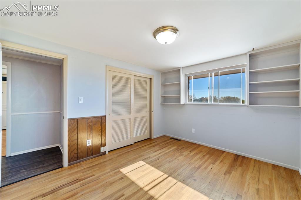 Image 22 of 49: Unfurnished bedroom with light wood-style floors, a closet, and wainscoting
